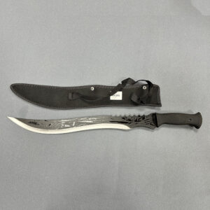 ​​Full tang machete with long curved blade featuring serrated back edge and textured black handle alongside fabric sheath with carrying strap