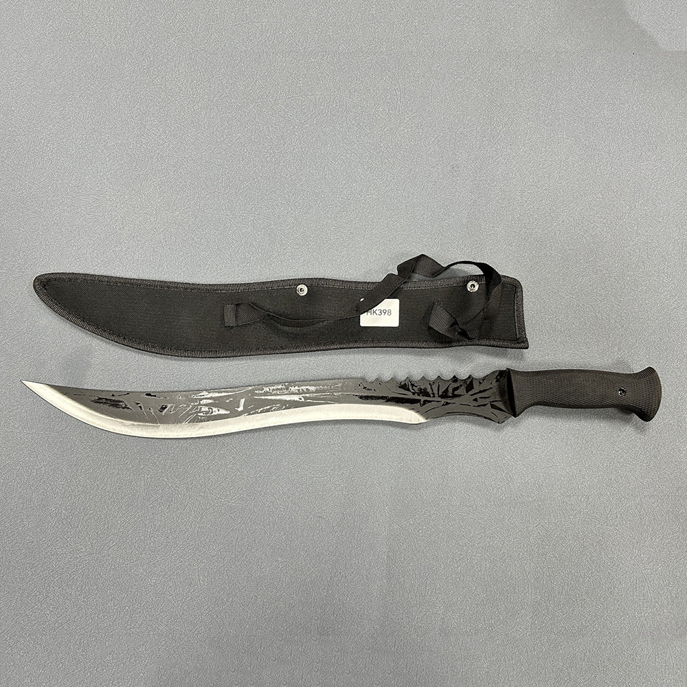 ​​Full tang machete with long curved blade featuring serrated back edge and textured black handle alongside fabric sheath with carrying strap